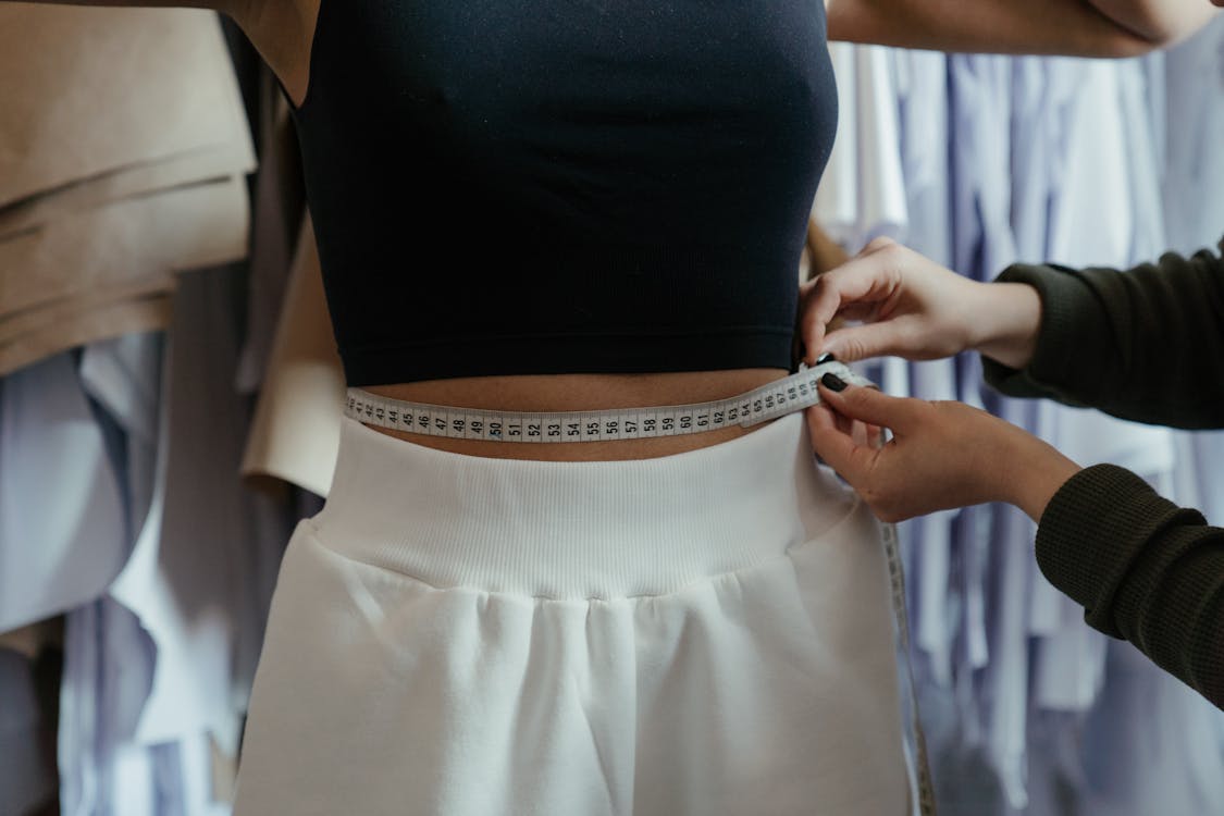 Person measuring waist circumference to track body contouring results