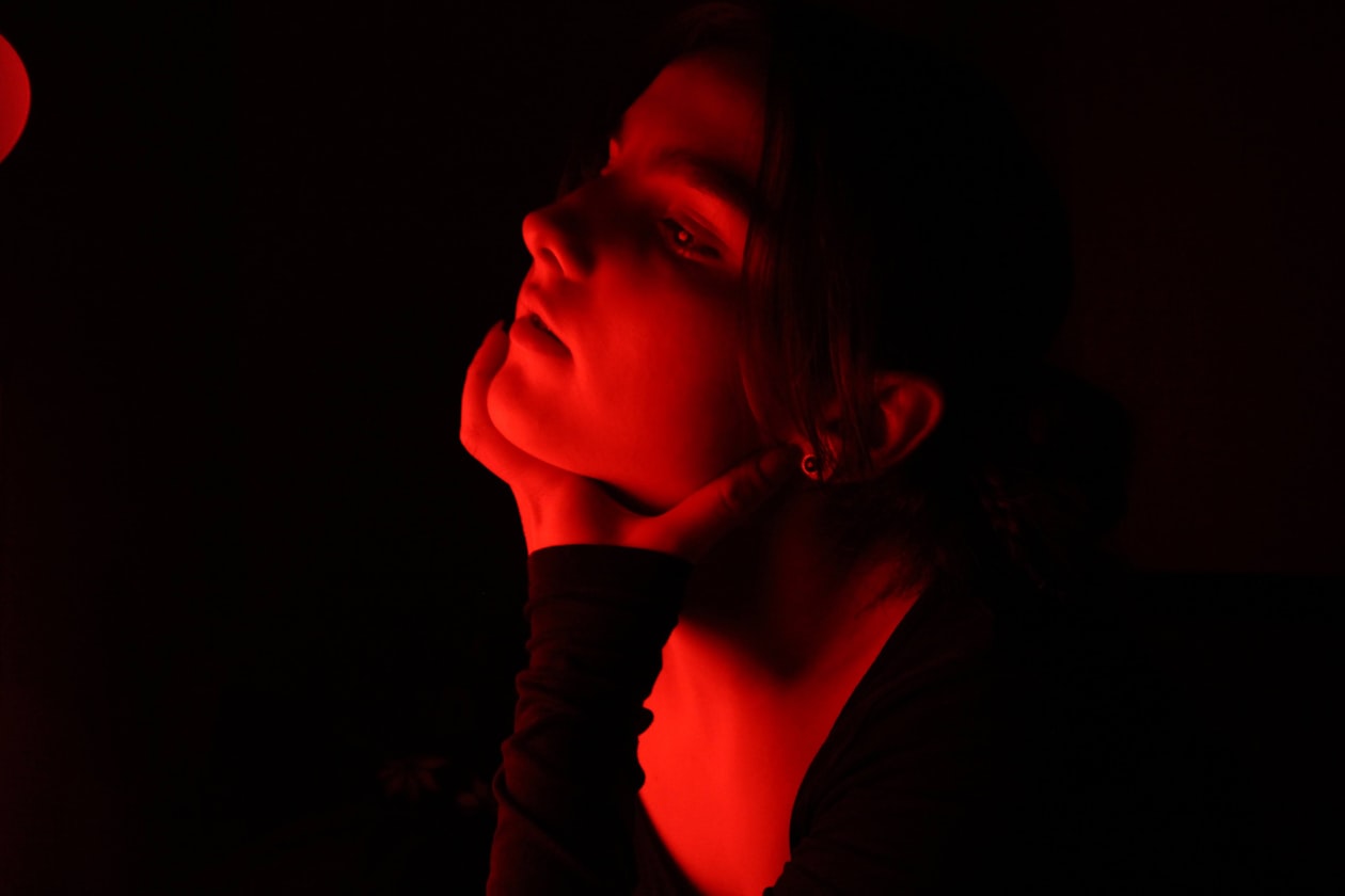 Woman's face bathed in red light during a photobiomodulation therapy session