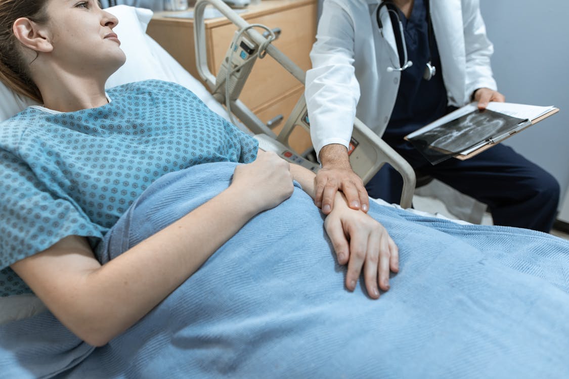 Doctor comforting a patient recovering in a hospital bed